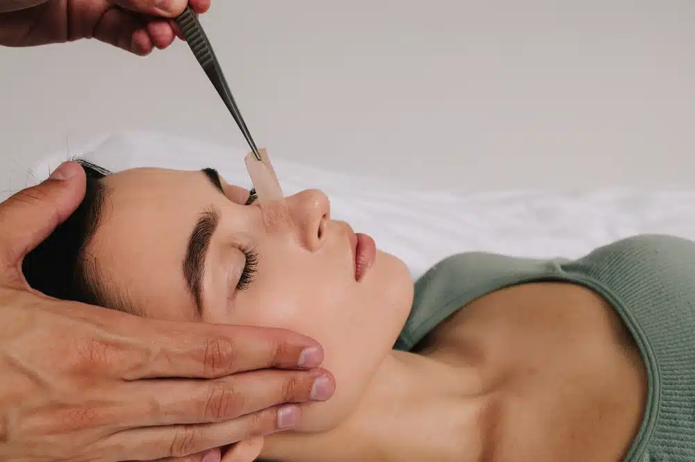 Close-up of surgeon assessing patient’s nasal structure during revision rhinoplasty consultation after healing period.