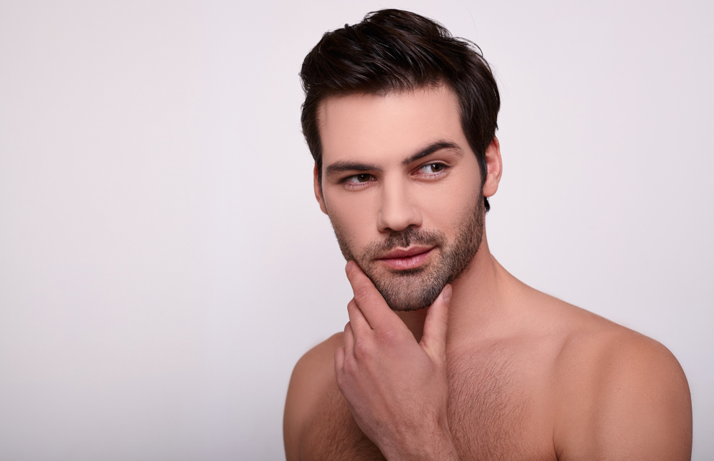 Man with well-defined chin and jawline touching his face, showing results of natural-looking male chin implant